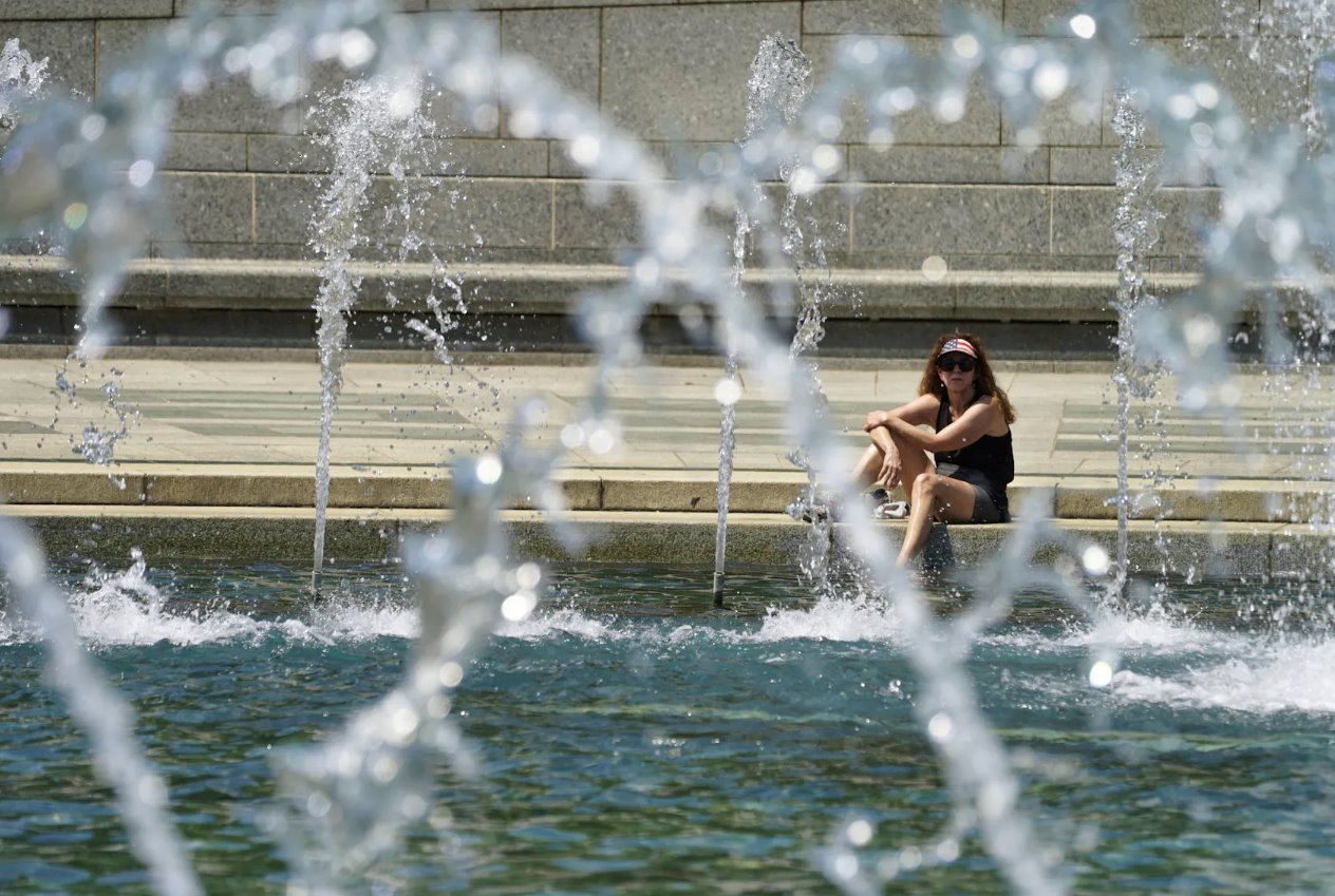 2024年4月29日,美國華盛頓,在可能創(chuàng)紀(jì)錄的高溫日,一名戴著星條旗遮陽帽的女士將腳浸入二戰(zhàn)紀(jì)念館的涼爽噴泉中。